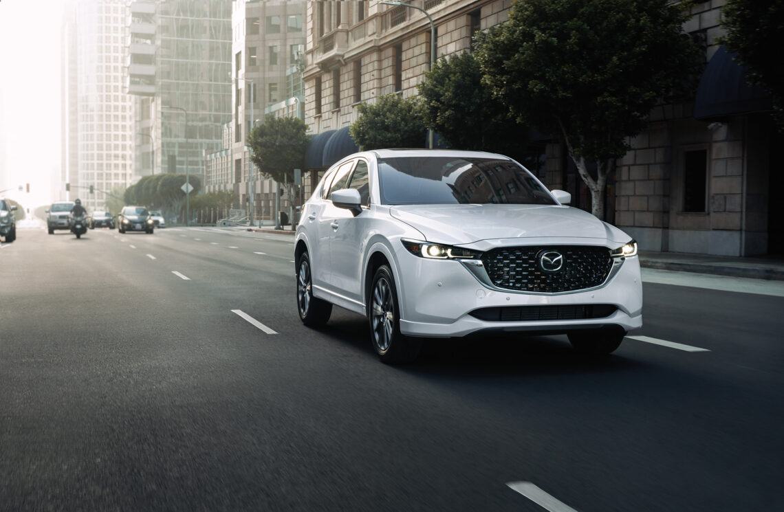 White Mazda CX-5 driving down a city street