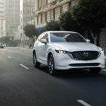 White Mazda CX-5 driving down a city street