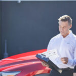 Female car owner and male service technician talking in front of Mazda car at service center